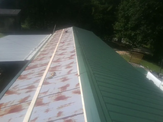 Old rusted panels beside newly installed green metal roofing — Wind Damage Roof Repair by Roofing Brothers in La Prairie