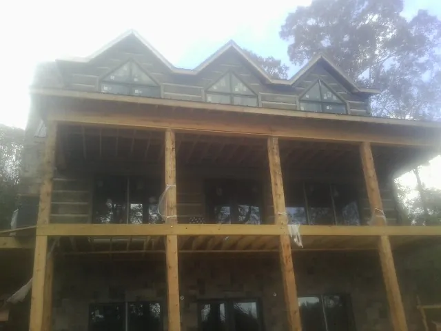 Dormers and porch framing on a large log home under construction — Roof Coating work by our crew in La Prairie