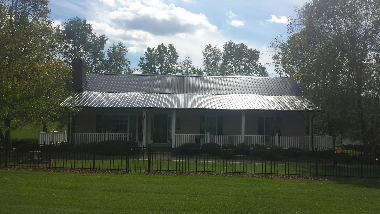 Gray metal roof on a brick ranch with a full width front porch — Gutter Guard Installation work by our crew in La Prairie