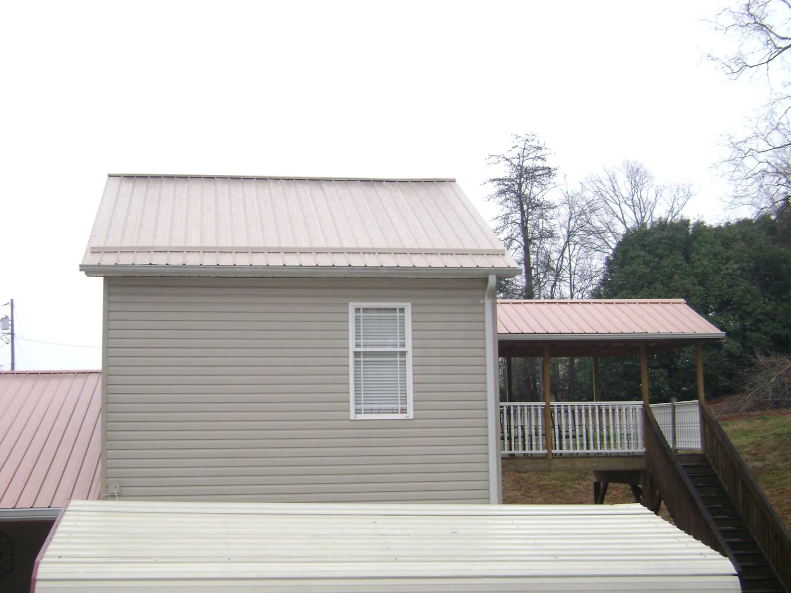 Tan metal roofs on a two story addition and attached porch, from a Roof Replacement job in La Prairie