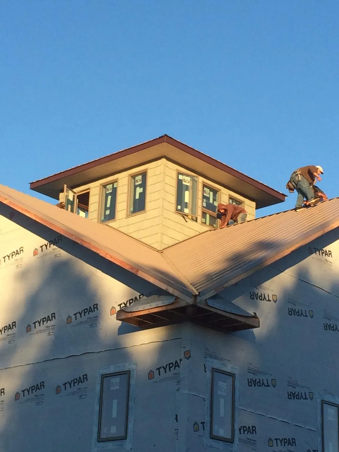 Roofers working around a rooftop cupola on a new metal roof at sunset — Roof Waterproofing in La Prairie by Roofing Brothers